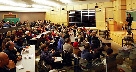 Tom Hawthorn addressing a large crowd in a lecture theatre