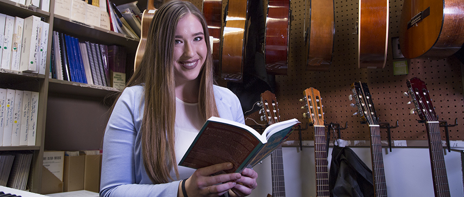 Jilaine Orton reading a music book with instruments in the background