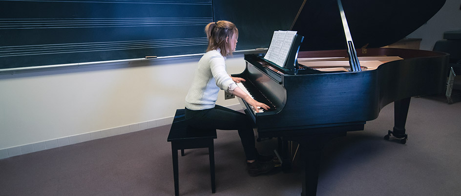 Female student playing a piano in a classroom