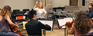 A conductor leading a small group of musicians in a classroom