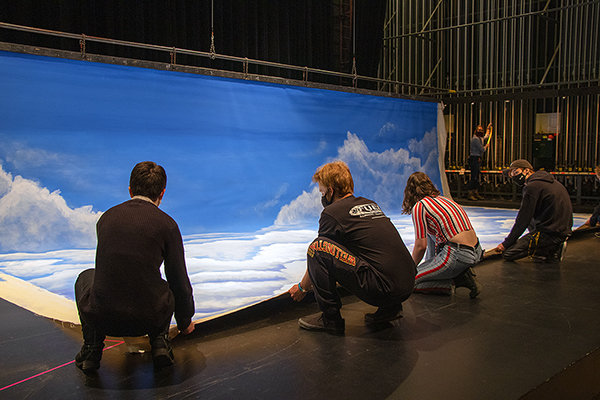 Students get ready to fly a hand painted backdrop for Dead Man's Cell Phone.