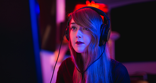 MFA student Kaitlyn Dunsmore with headphones on looking at a computer screen
