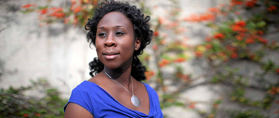 Writing alumna Esi Edugyan in front a building wall covered in vines and flowers