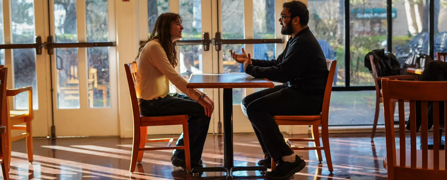  Charlotte Davidson and Fawzan Hussain sit across from another at a table 