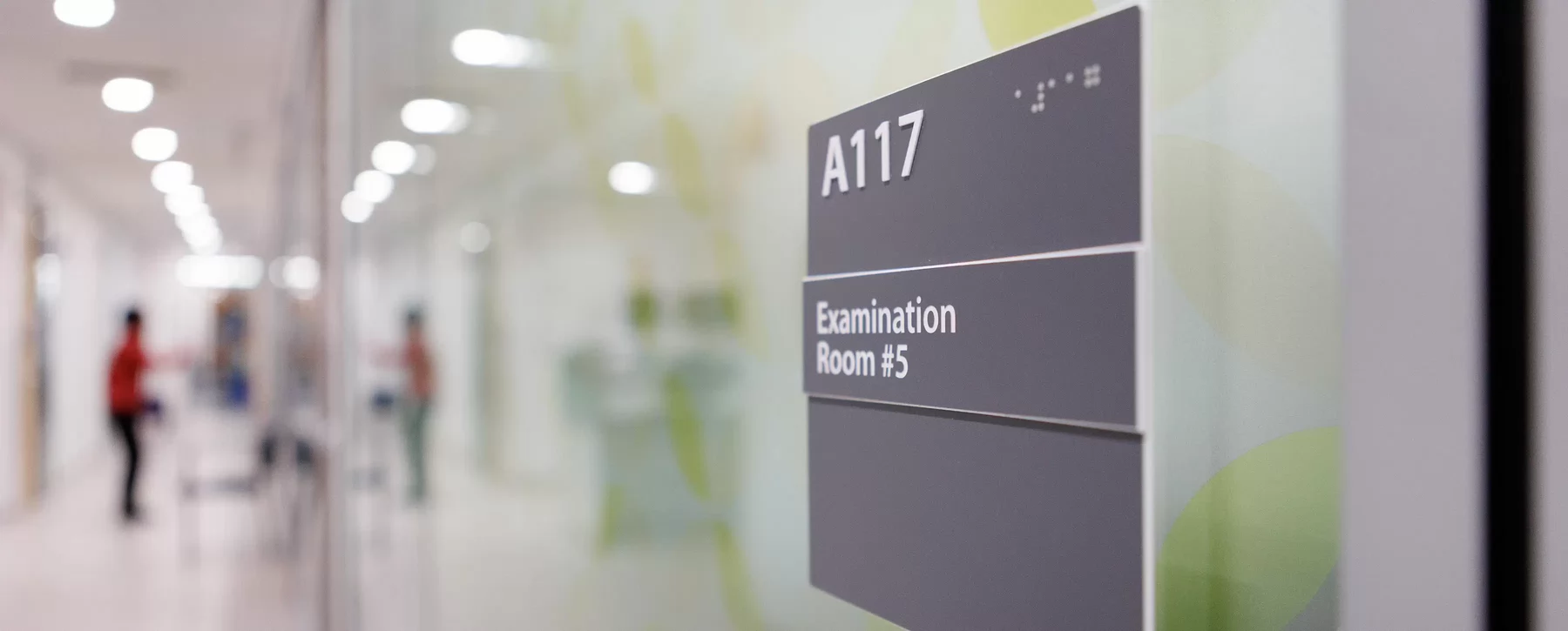 A hospital hallway with the focus on a sign on the door that says Examination Room #5.