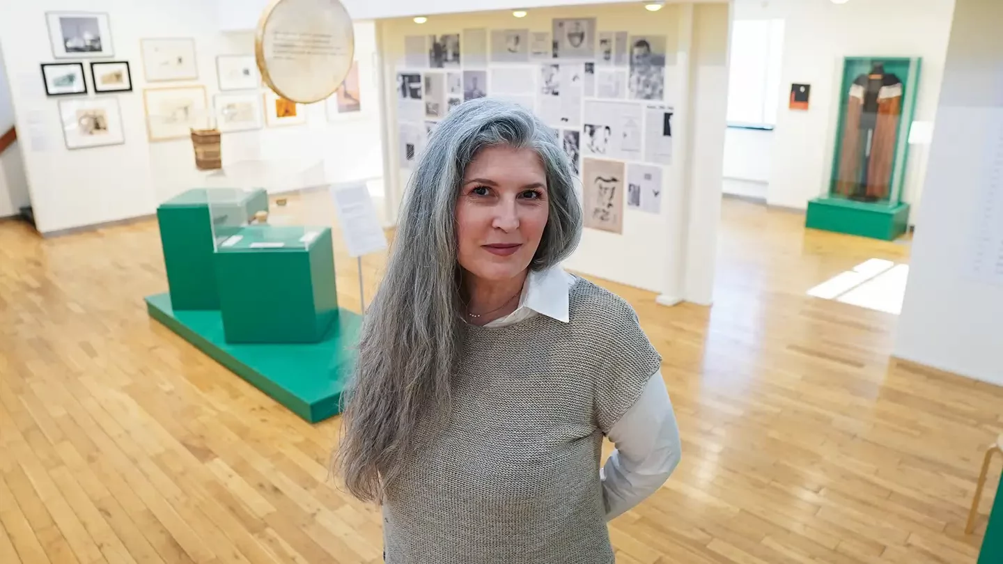Woman with long hair smiling and standing in an art gallery.