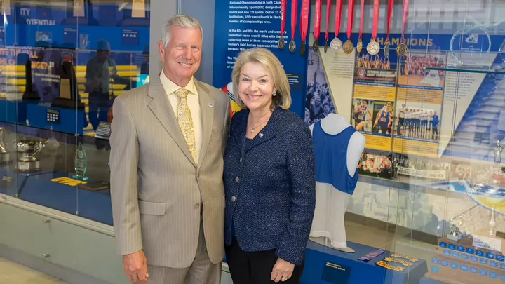 Murray and Lynda standing in the CARSA building with medals and trophies behind them