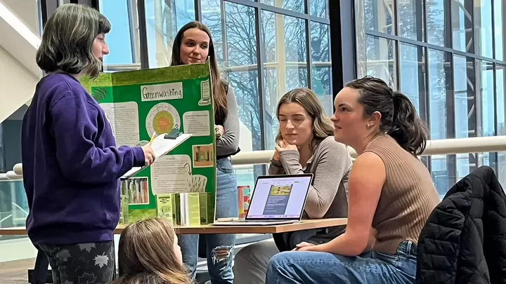 Five undergraduate students gather at a learning station about greenwashing at the Royal BC Museum.