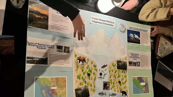 A poster board shows a landscape illustration containing water, mountains, bears, fish, trees and a fisher.