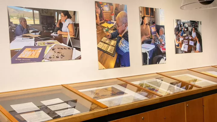 Photos of Indigenous Elders on a wall above a glass display case.