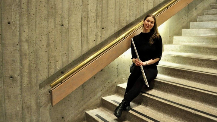 Student sitting on stairs with her flute