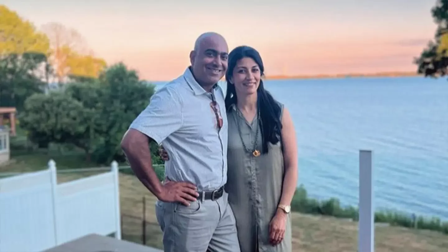 Samit and Reshma standing together by an ocean view at sunset