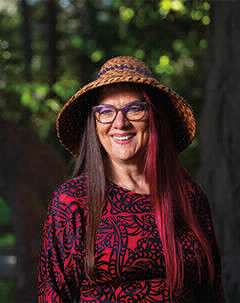 A woman wearing glasses and a woven Indigenous hat smiling.