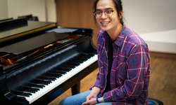 Lucas Hung sits at a piano smiling