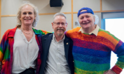 Dr. Aaron Devor stands smiling in the middle of two attendees at the Moving Trans History Forward conference.