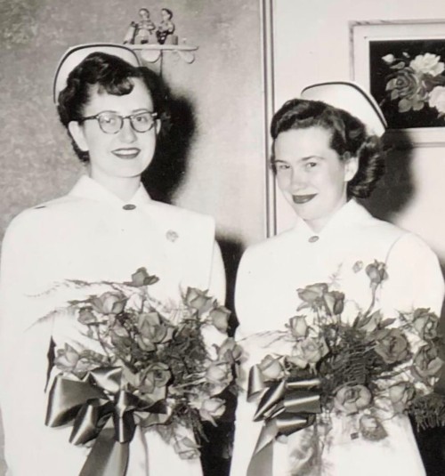 A black and white photo of Elta Brown and Peggy Mika in nurses uniforms holding bouquets of flowers