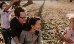 A man and woman sit on grass smiling at two children