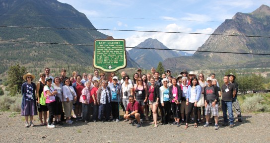 The bus tour group stand by the memorial plaque in East Lillooet
