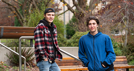 Two male students stand on the steps outside the university's Bob Wright building.