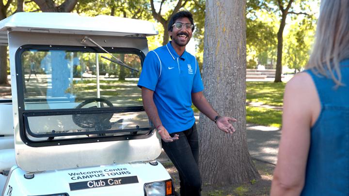 Driver of a UVic Campus Tours club car offers a student a tour