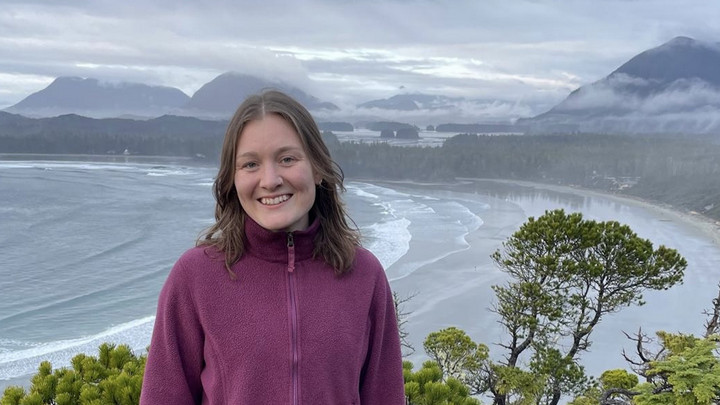 Sustainability Scholar Mary Stuart pictured smiling with a view behind of ocean and mountains