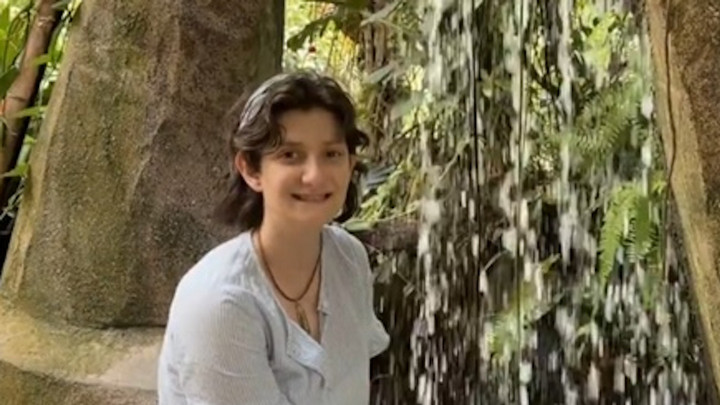UVic Sustainability Scholar, Sabrina Francescangeli, pictured in a forest sitting in front of a waterfall