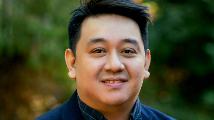 Profile picture of sustainability scholar Carlos Garcia smiling with green background