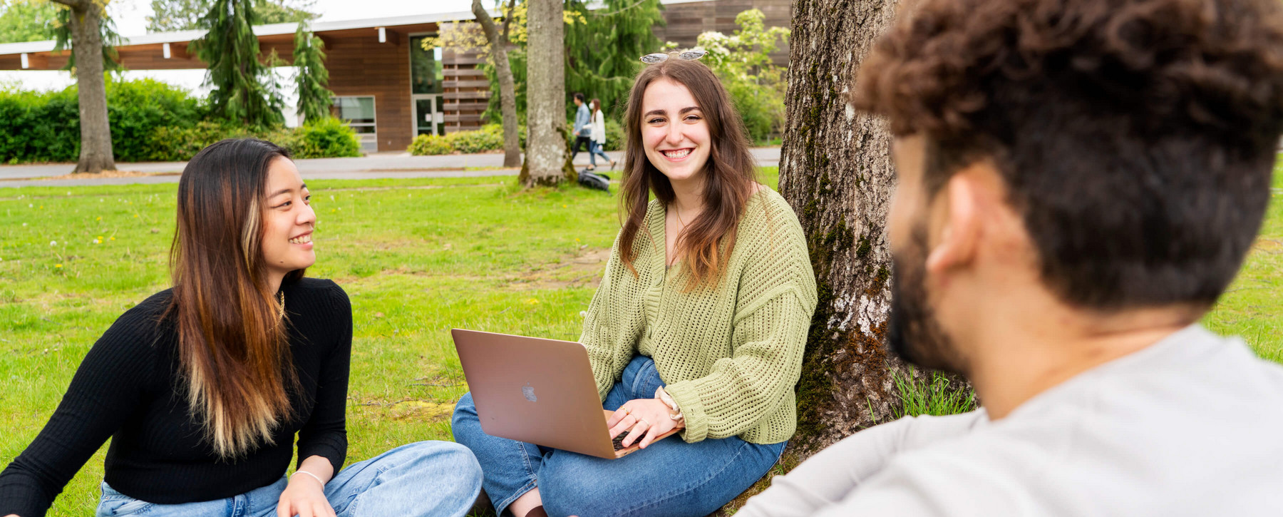 BCom students sitting outside by the trees
