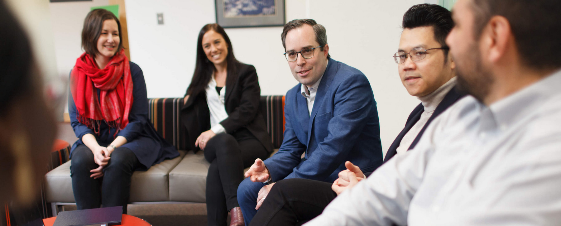 PhD students, faculty and post-doctoral researchers chat on couches