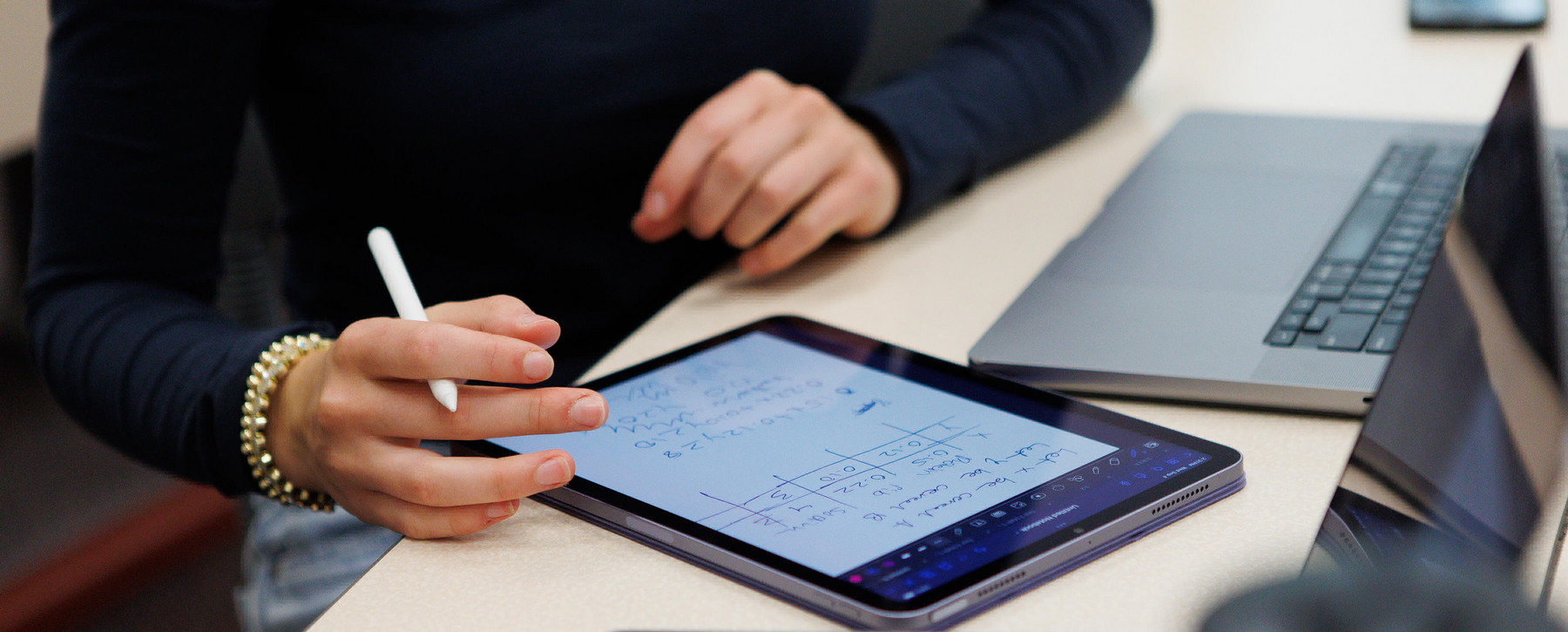 Student taking notes on tablet in classroom