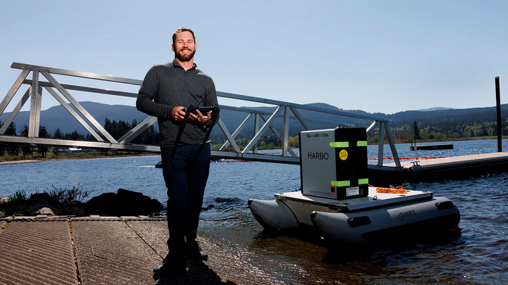 Brant Chlebowski operating a robot boat from the shore