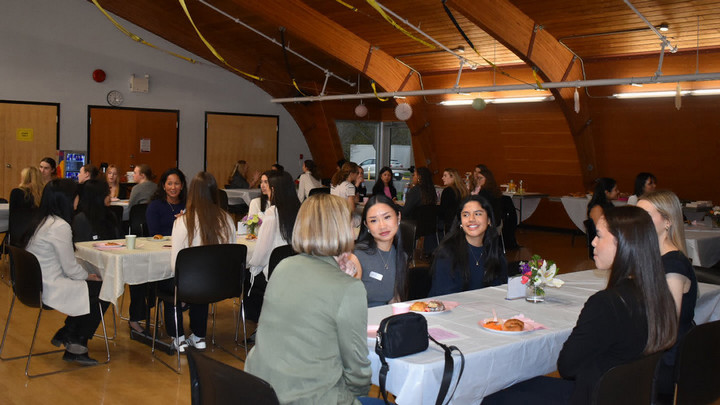 The members of the UVic Girls that Invest club chatting around tables at an event