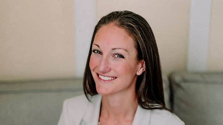 Jen Scharien smiling and sitting on a couch
