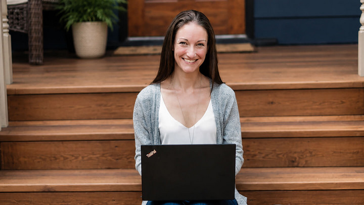 Jen Scharien sitting on the stairs to a house with a laptop
