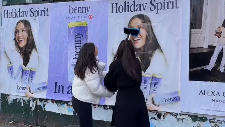 Paige Cey and Julie Letizia put up some giant posters on a wall