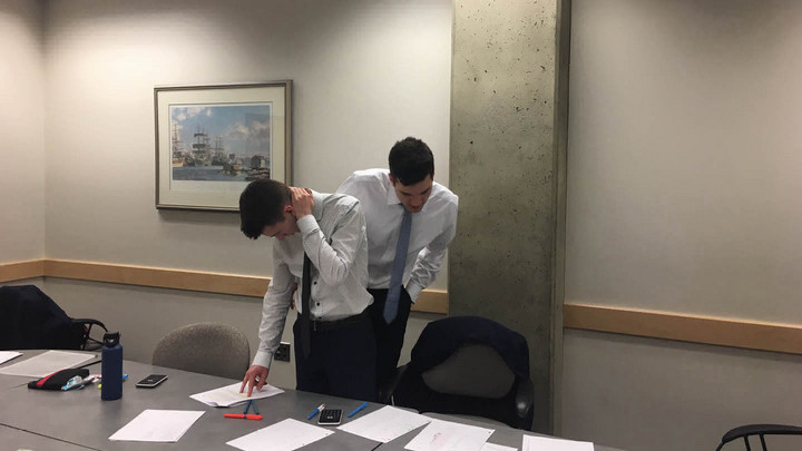Two members of Team 58 review the case around the boardroom table