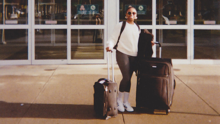 Safi Morisho at the departure entrance at the airport with her luggage in tow