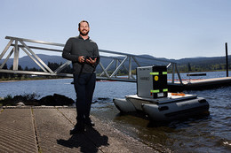 Brant Chlebowski operating a robot boat from the dock