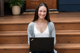 Jen Scharien sitting on the stairs to a house with a laptop