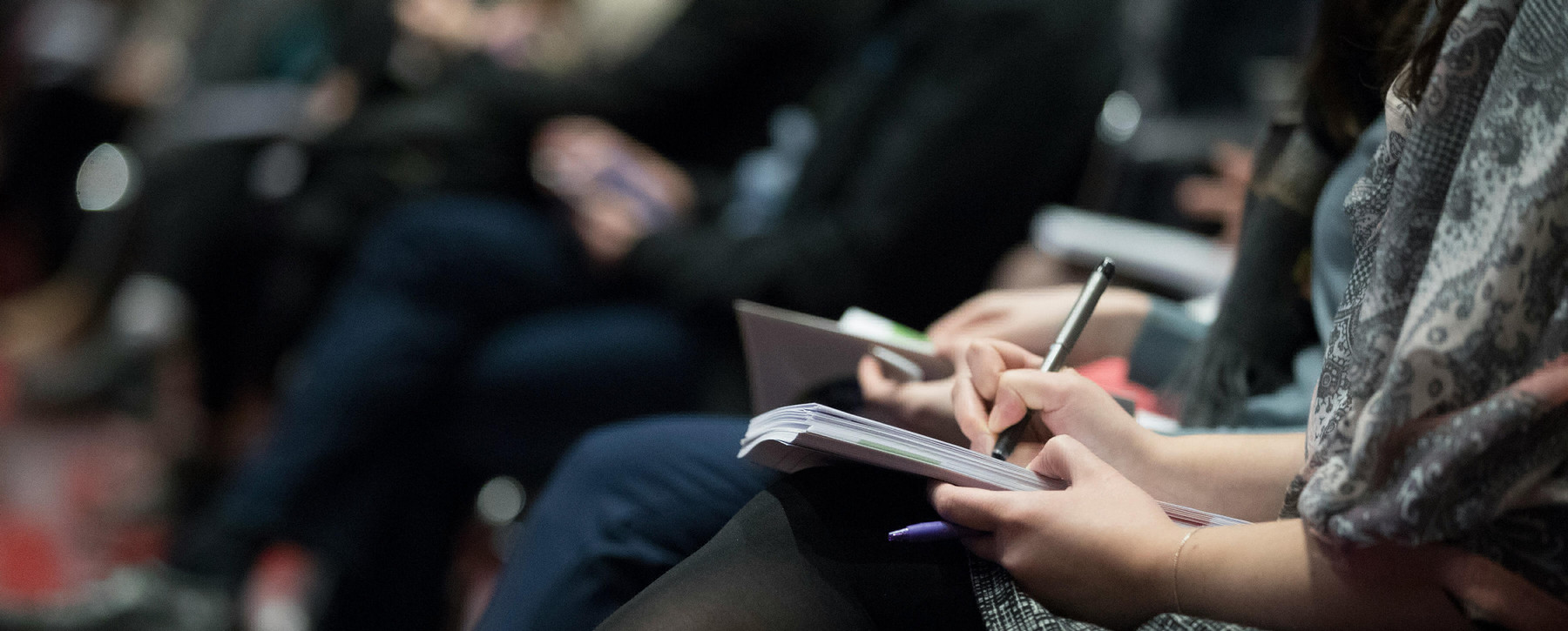 Attendees seated at a conference taking notes