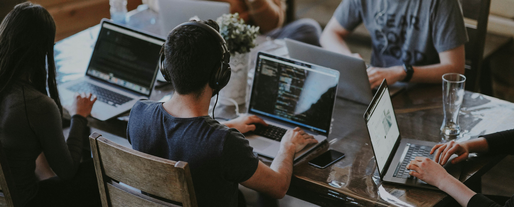 Office workers working on laptops around boardroom