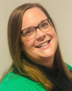 Woman with brown hair and glasses smiling