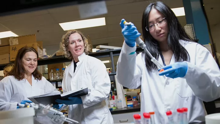 Three woman in white lab coats performing lab work 