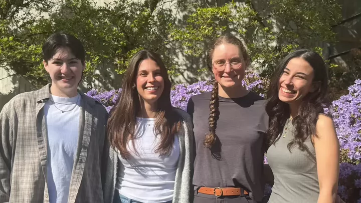 Four medical science students standing in a row, smiling