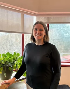 Portrait of Heather Baid wearing a black shirt, in front of a window