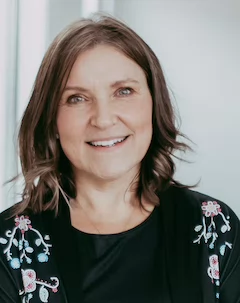 Portrait of Brenda J Mishak wearing a black shirt with floral design.