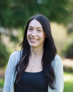 Alisha Teddy smiling and wearing a black blouse under a grey cardigan.