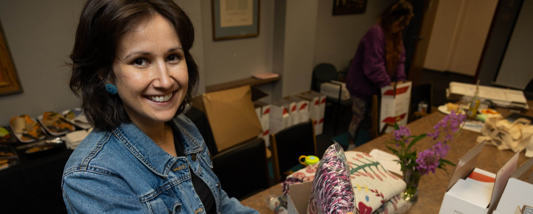 Willow Paul, a woman with dark hair and denim jacket, facing the camera and smiling