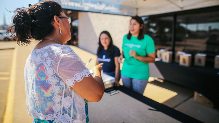 Three women talking under an event tent
