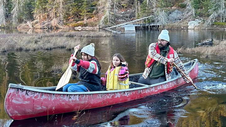 Mathew Hupfield steers a canoe with his family at the helm